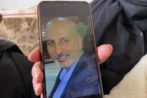 Aamir Peerzada/BBC A photo of a bald man with a moustache is seen on a mobile phone screen