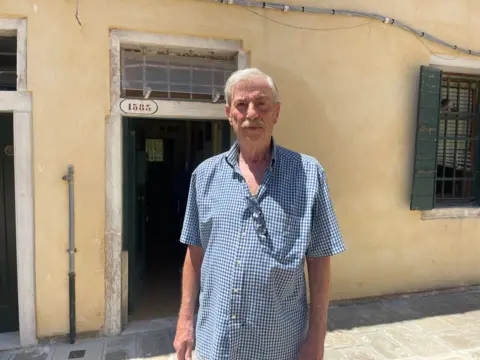 Roberto, who is in the seventies, standing in front of the building in Venice