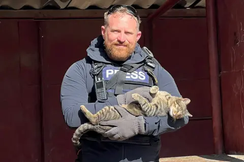 Reuters Reuters safety adviser Ryan Evans holds a cat that he found while working with a news reporting team