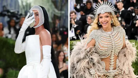 Katy Perry in white with a white mask on her face in a style similar to a fencer's mask and Beyonce Knowles in an ornate silver and diamond studded gown with head-dress 