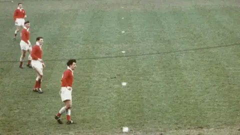 Four Wales players, including Bryan Richards at the front, on a pitch in 1960