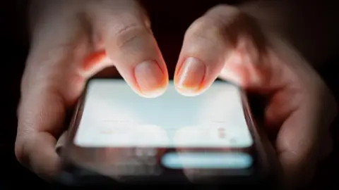 Getty Images A zoomed in shot of a person texting on their smartphone