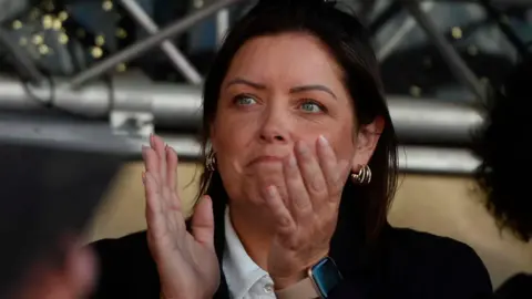 PA Media A woman with dark hair and clothing claps