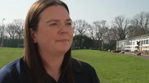 Lisa McCormick, a woman in a blue t shirt with long dark hair, standing on a football pitch