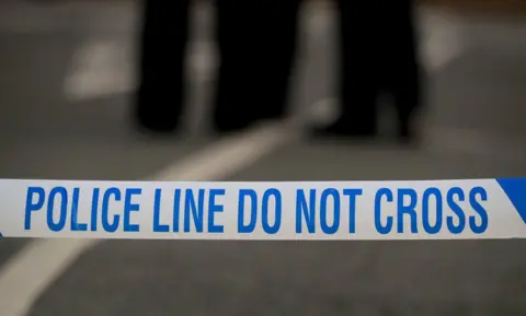 Close-up of police tape which reads "Police line, do not cross".