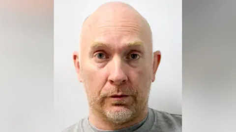 Met Police Mugshot of Wayne Couzens, a middle-aged man with balding hair and ginger beard 