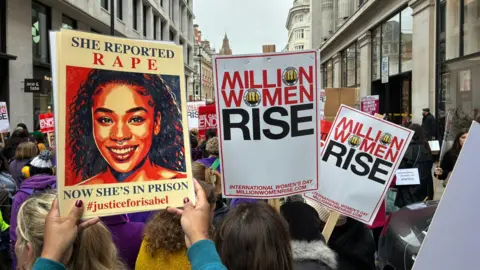 Lilly Crick A group of people on a protest march in London holding placards. 