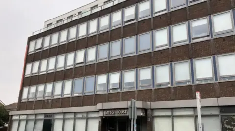 An image of Imtech House in Woodthorpe Road, Ashford. It is a multi-storey building with many windows. There is a grey sky in the background. 