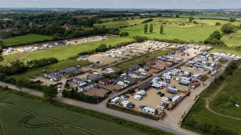 Ant Saddington/BBC An aerial view of lots of caravans and static homes on brownfield land, surrounded by green fields.