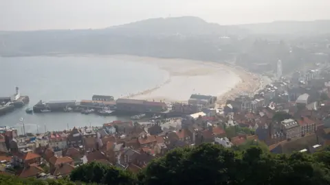 Scarborough beach and pier, pictured from above on a misty day.
