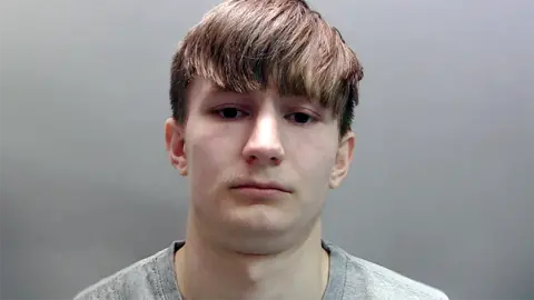 A mugshot of Jack Crawley. He has short brown hair and is wearing a grey T-shirt.