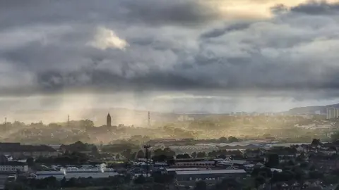 Lawrie Mcinally Grey clouds with misty rain hang over Glasgow. The city is pictured from far away with many buildings and structures peaking through the mist of the rain.
