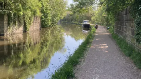 Canal and River Trust A canal side with a gravel path on a sunny day