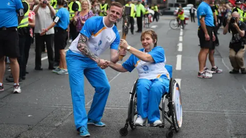 Getty Images Ross Nixon and Dr Margo Whiteford, who is in a wheelchair, carry the Queens Baton Relay as it arrives in Glasgow on August 20, 2014.
