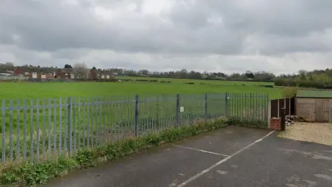 Google Open fields off Alfreton Road in Selston, fenced off with a car park at the front of the image.