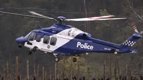 A police helicopter takes off over a vineyard