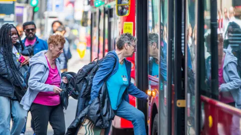Getty Images People boarding in to bus at bus stop, City of London - stock photo