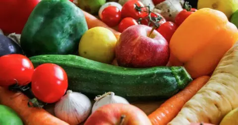A picture of fruit and vegetables, including tomatos, apples and carrots.
