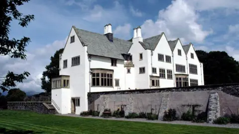 Lake District National Park Authority Blackwell - a large house painted white with a grey roof. A trimmed lawn runs alongside the property.