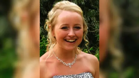 Family Handout Ella is smiling at the camera ahead of attending her school prom. She has blonde hair which is tied back in a low bun and two curled bits of hair framing her face. She has a diamond necklace on and a sequin top dress.