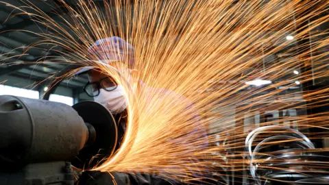 A worker wearing a face mask works on a production line manufacturing bicycle steel rim at a factory in Hangzhou, Zhejiang, China. 