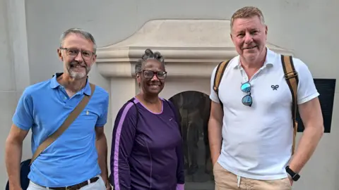 Tim Parry, Patricia Windham and Peter Tidmarsh pose in front of the London Stone at 111 Cannon Street, London