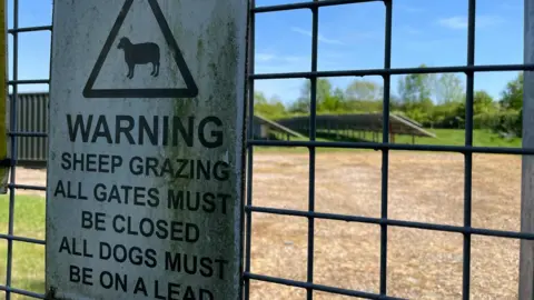 A sign about grazing sheep on the fence of a solar farm