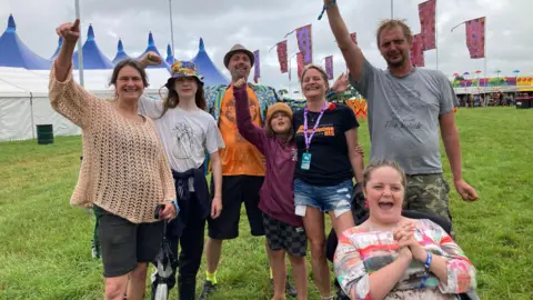 Team of volunteers punch the air in front of the flags and performance tents