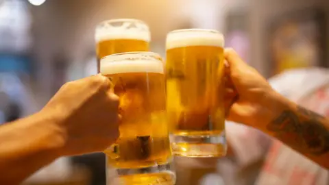 Getty Images Three people clinking glasses of beer and saying cheers