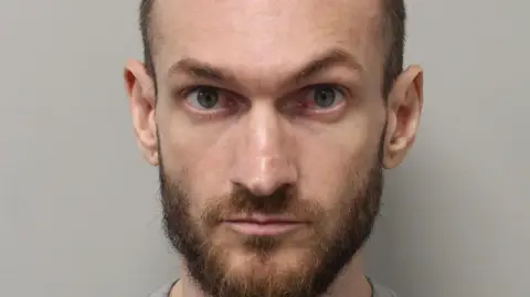 Met Police A mugshot of Marcus Arduini Monzo who has been found guilty at the Old Bailey of murdering 14-year-old Daniel Anjorin. He is wearing a grey jumper and is starring directly at the camera with a fuzzy beard