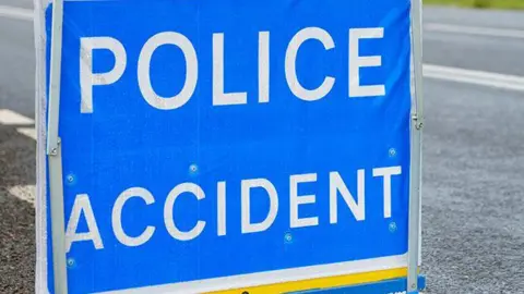Police accident sign on a road, with bold white letters saying POLICE ACCIDENT on a blue background.