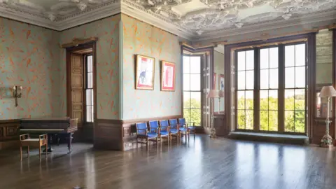 Knight Frank Another wood-panelled room with large windows and a piano in the corner