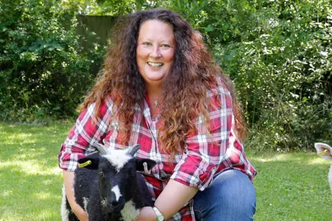 Vista Beth Brook wearing a red checked shirt holding a goat