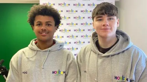 Jake and Thomas both wear grey hoodies with the Horizon logo on them and are smiling for the camera.