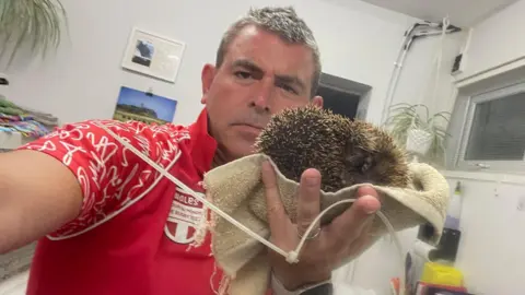 GSPCA Steve Byrne holding the hedgehog and the cut cable tie after it was removed