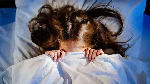 Girl hiding under duvet