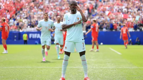 Simon Stacpoole / Offside A footballer stands square on to the camera, one arm across his body, the other pointing to his head