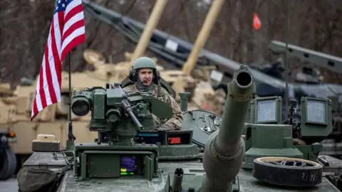 A US soldier rides on a tank in Grafenwoehr, Germany. Photo: February 2025