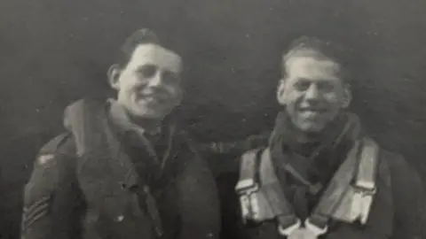 PA Media A black and white image of two men standing next to each other and smiling at the camera.
