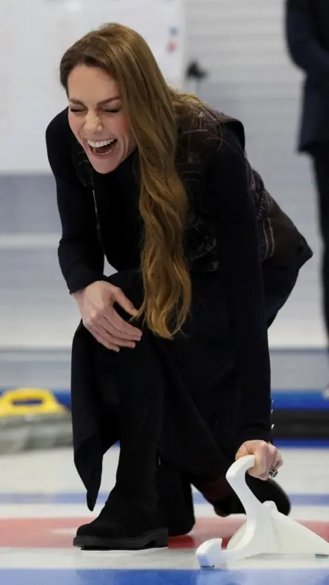 PA Media The princess is crouching on the curling rink holding a piece of equipment with a huge grin on her face. 
