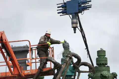 Getty Images Seorang pekerja di Pennsylvania membersihkan mesin fracking.