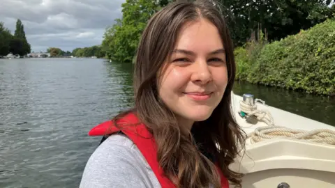 Izzy Wittrock sits on a boat and smiles at the camera