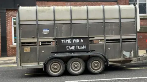 Julia Lewis/BBC A trailer on a car saying "Time for a Ewe-turn"