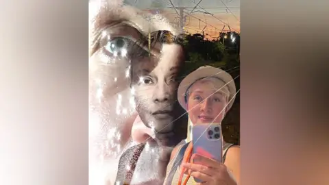 Women of the World/Irina A women holding a phone, wearing a hat, with light reflections in the background