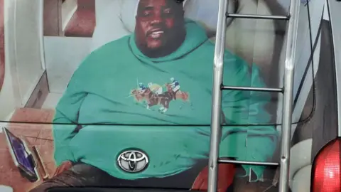 A minibus taxi in Harare with its back painted with a big portrait of Sir Wicknell in a green long-sleeve top with polo players on its front.
