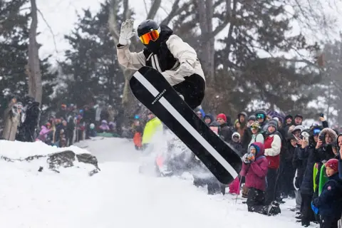 Shaun White does a snowboard flip in front of onlookers.