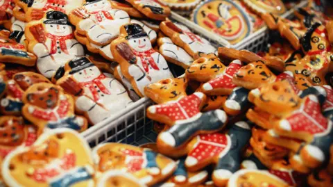 Handmade Christmas decorations to hang on a Christmas tree. They are for sale in a market, with teddies and snowmen in the image.