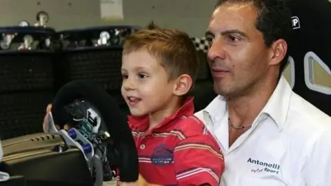 A young Kimi Antonelli sitting on his dad's lap while steering a car