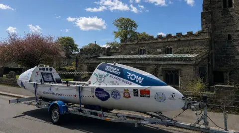 Louis Webb The large white sailing boat parked outside a traditional-looking church on a sunny day