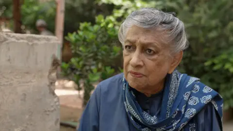 Uma mulher olha para um ponto à esquerda da câmera